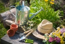 Садовые принадлежности и соломенная шляпа на траве в саду