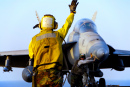 Матрос направляет истребитель F-18 Хорнет